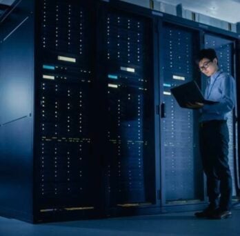 person using laptop in server room
                  